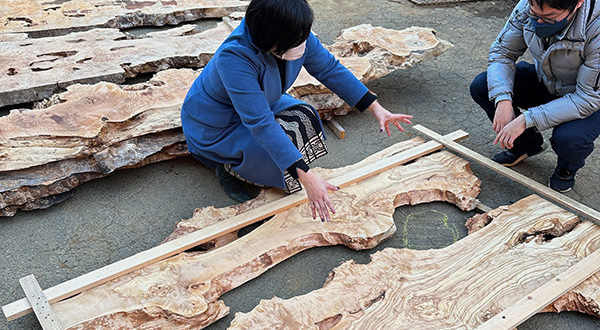 お客様がレジンテーブルの木材配置を楽しみ両手でデザインを確認している写真